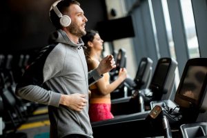 A young man listening to music to stay motivated and complete a workout at the gym.