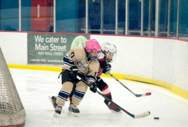 Alexis Oliveira (in the pink helmet) fighting for the puck battle at William G. Mennen Sports Arena wearing blue and gold for Roxbury Youth Ice Hockey.